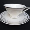 White teacup and saucer with silver trim.