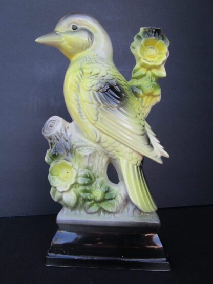 Ceramic bird figurine on branch with flowers.