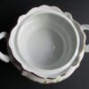 A white bowl with two handles on the bottom.
