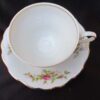 A white tea cup and saucer with flowers on it.