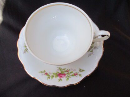 A white tea cup and saucer with flowers on it.