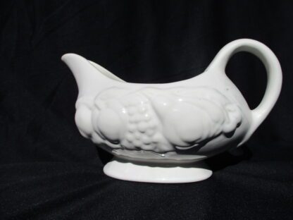 A white ceramic pitcher sitting on top of a table.